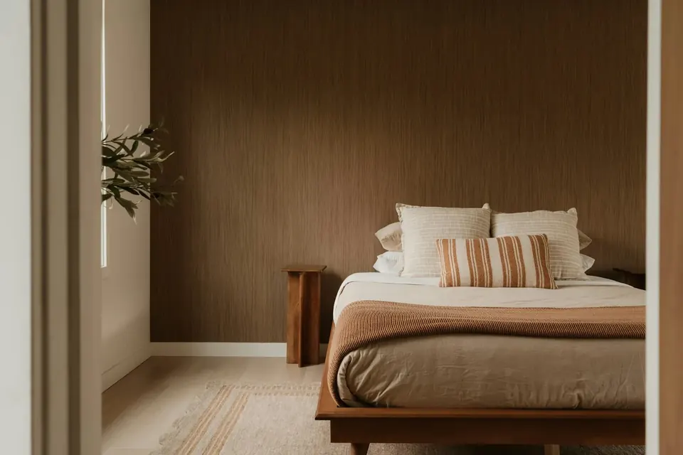 Ruhiges Schlafzimmer mit warmer Holzwand und frisch bezogenem Bett